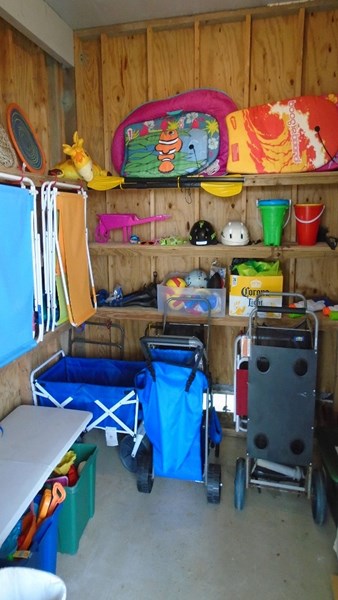 The shed contains a wagon, carts, umbrellas, beach chairs and toys.