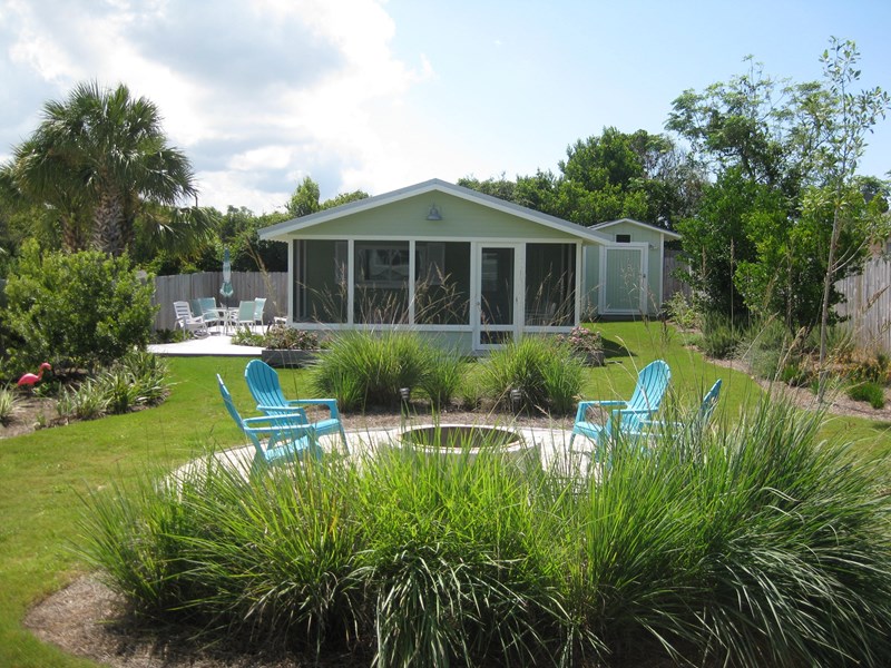 Hideaway cottage front view- tucked away in fully fenced garden, quiet & private! Fire pit in foreground.